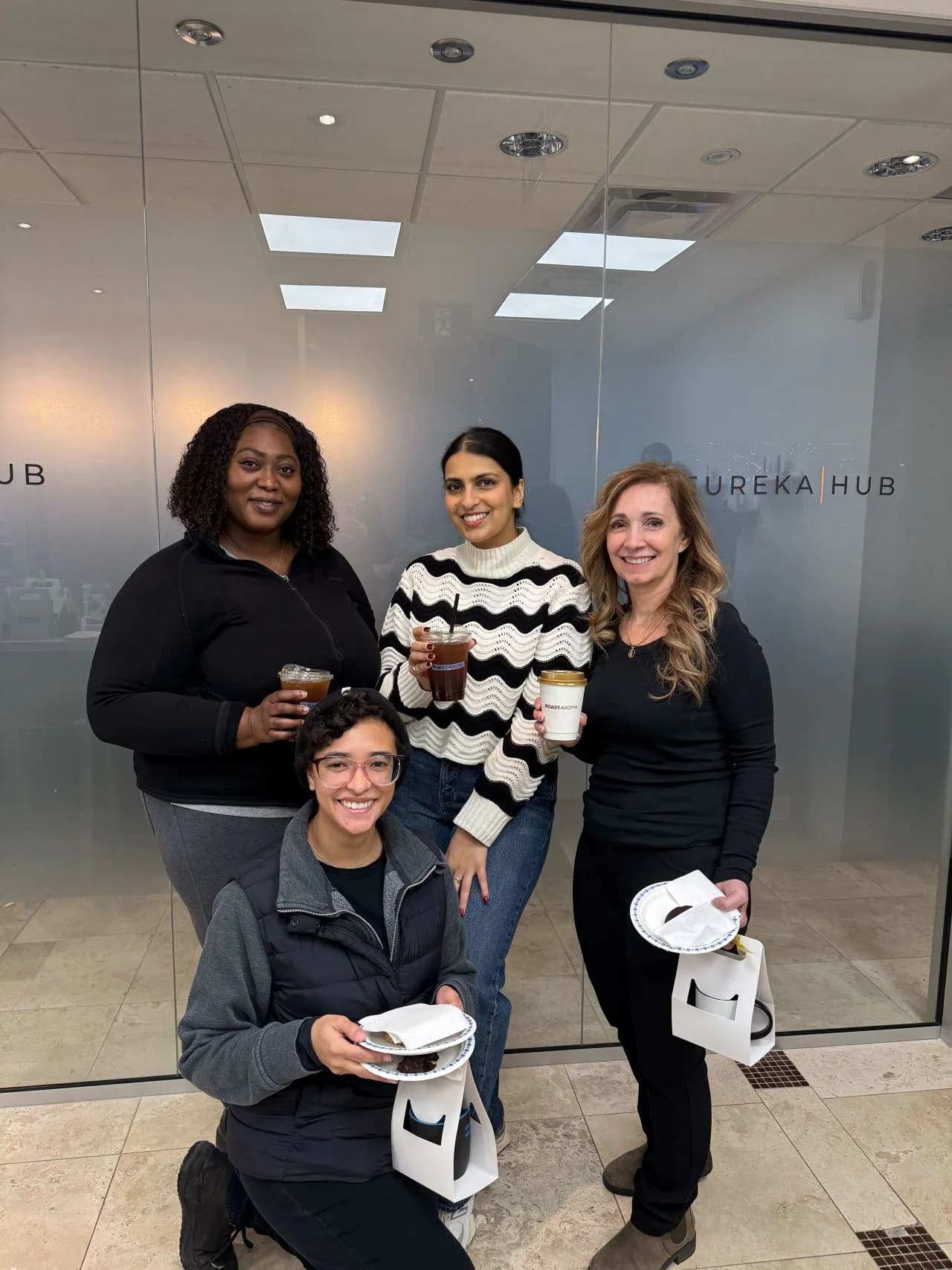 Four attendees holding RoastAroma drinks at a workplace event