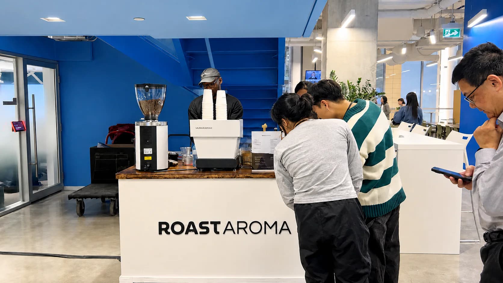 Guests ordering from a RoastAroma coffee cart at an indoor event